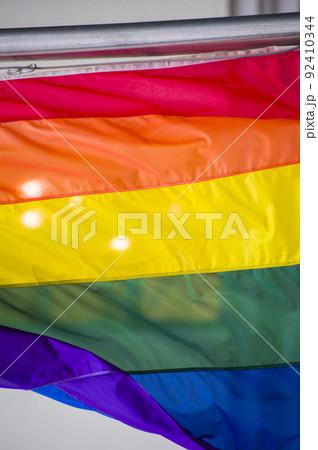 Close Up rainbow gay pride flag outside on a street. Symbol of the Lesbian Bisexual Transgender LGBT community waving in wind against cloudy sky. Social movement for freedom and equliaty. Copy Space Close Up rainbow gay pride flag outside on a street. Symbol of the Lesbian Bisexual Transgender LGBT community waving in wind against cloudy sky. Social movement for freedom and equliaty. Copy Space 92410344