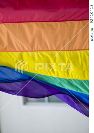 Close Up rainbow gay pride flag outside on a street. Symbol of the Lesbian Bisexual Transgender LGBT community waving in wind against cloudy sky. Social movement for freedom and equliaty. Copy Space Close Up rainbow gay pride flag outside on a street. Symbol of the Lesbian Bisexual Transgender LGBT community waving in wind against cloudy sky. Social movement for freedom and equliaty. Copy Space 92410418