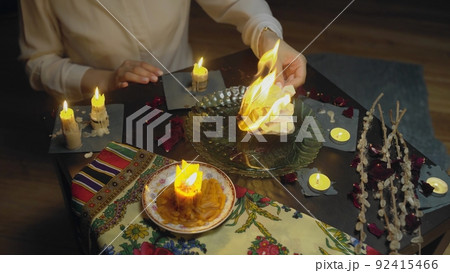 4K. Top view of the table with candles. Women's hands set fire to paper 92415466