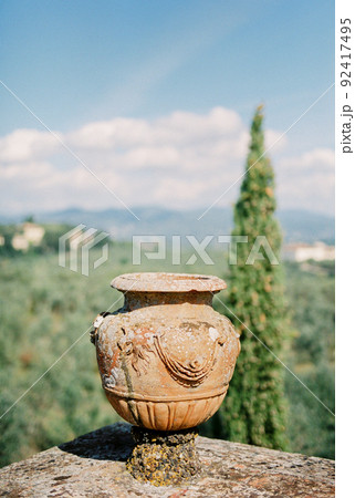 Clay amphora on a stone fence in the garden. Florence, Italy Clay amphora on a stone fence in the garden. Florence, Italy 92417495