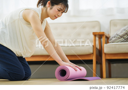 ヨガマットを巻く女性 92417774