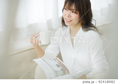 自宅でコーヒーを飲みながら雑誌を読む女性 自宅でコーヒーを飲みながら雑誌を読む女性 92418082