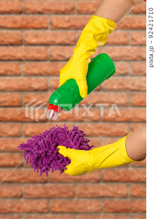 Women's hands in protective gloves with bottle of washing liquid. 92421710