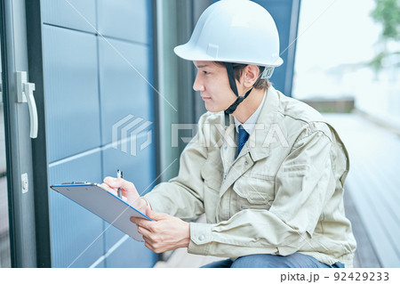ドアをチェックする作業服姿の若い男性 92429233