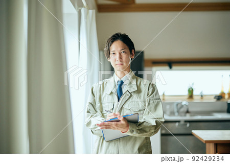 キッチンの前でバインダーを持って立つ作業服姿の営業マン 92429234
