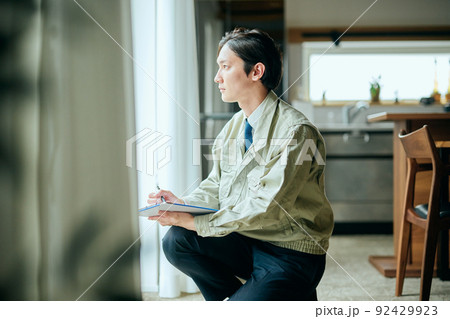 窓をチェックする作業服姿の若い男性 92429923