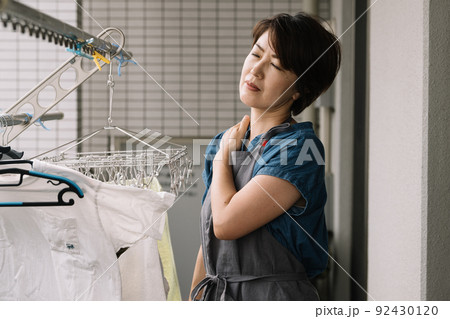 家事をしながら肩こり・ストレス・疲労を感じる主婦 92430120