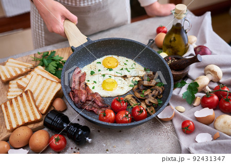 Fried eggs and bacon on a pan at domestic kitchen 92431347