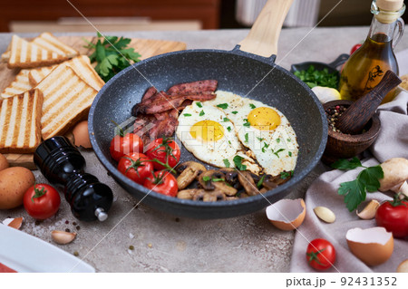 Fried eggs and bacon on a pan at domestic kitchen Fried eggs and bacon on a pan at domestic kitchen 92431352
