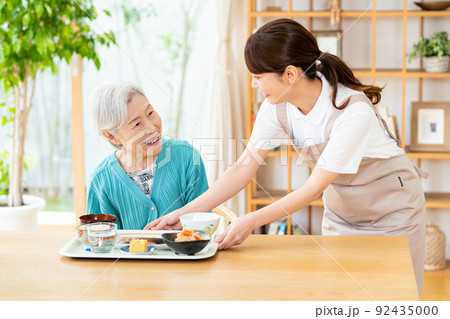 食事するシニア女性とヘルパーの女性 92435000