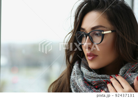 Young beautiful woman in scarf, warming hands, pensive look away, view from window Young beautiful woman in scarf, warming hands, pensive look away, view from window 92437131
