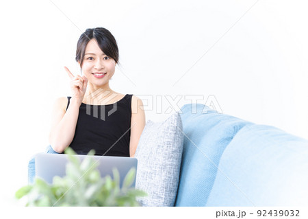ソファに座っておすすめする若い女性 92439032