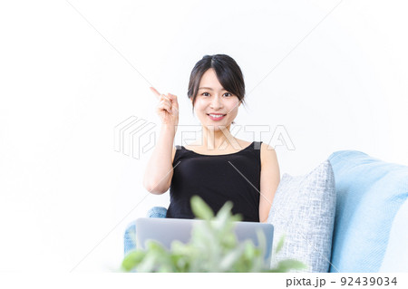 ソファに座っておすすめする若い女性 92439034
