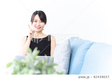 ソファに座っておすすめする若い女性 92439037