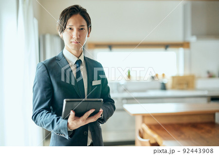 キッチンの前でタブレットを持って立つ住宅営業のビジネスマン キッチンの前でタブレットを持って立つ住宅営業のビジネスマン 92443908