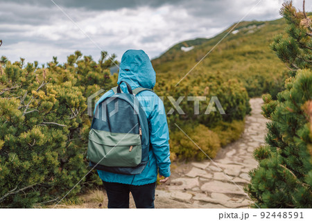 Man and woman hiking at mountains with sports backpack. Travel adventure concept. Group of female friends hiking in nature.  92448591