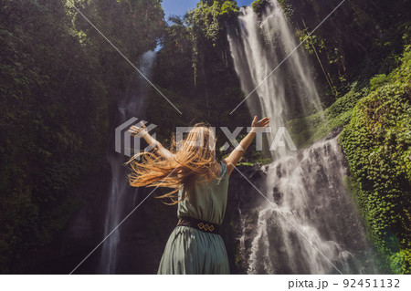 Woman in turquoise dress at the Sekumpul waterfalls in jungles on Bali island, Indonesia. Bali Travel Concept 92451132