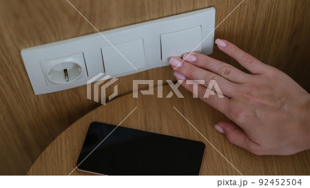Woman hand presses on turn off lights closeup 92452504