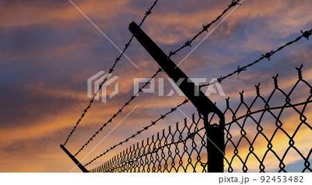 Barbed wire outline against a sunset orange sky 92453482
