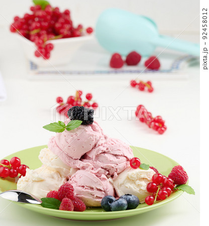 Vanilla and raspberry ice cream scoops on a round green plate 92458012
