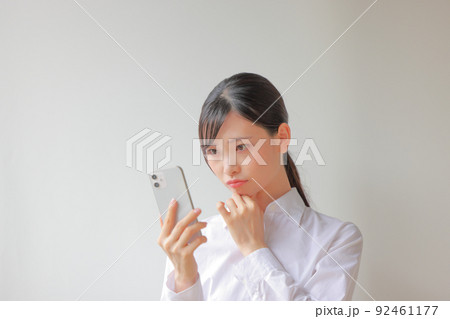 スマホを見て困っている表情の女性1 スマホを見て困っている表情の女性1 92461177