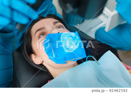 Closeup portrait of a female patient with a cofferdam system in a modern dental office. Dental equipment 92462592