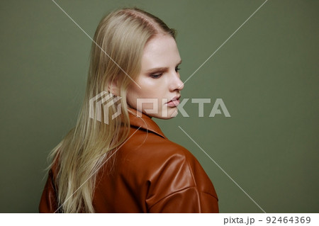 Unbelievable beautiful stylish woman posing in leather dress at over green studio background 92464369