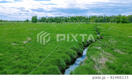 Small stream runs through a green grassy landscape Small stream runs through a green grassy landscape 92466115