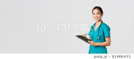 Healthcare workers, preventing virus, quarantine campaign concept. Smiling friendly female doctor, nurse in scrubs writing dorn results analysis at clipboard, standing white background 92466433