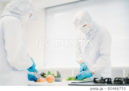 クリーンスーツで野菜のカットをする男女（食品加工） 92466753