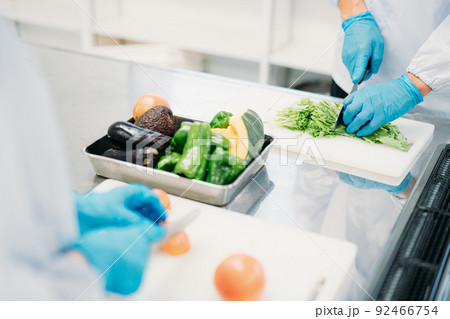 クリーンスーツで野菜のカットをする男女(食品加工・手元) クリーンスーツで野菜のカットをする男女(食品加工・手元) 92466754