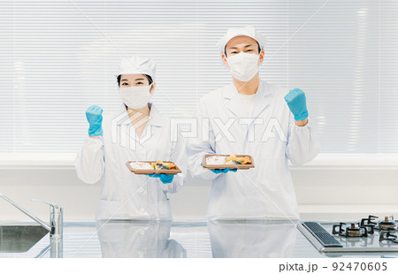 お弁当の盛り付けをする男女（食品加工・手袋・ガッツポーズ） 92470605