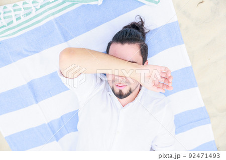 ビーチで寝転がる男性、熱中症、睡眠 ビーチで寝転がる男性、熱中症、睡眠 92471493