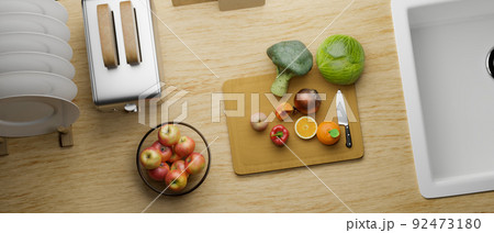 Overhead, A modern wood kitchen tabletop with vegetables and fruits slides on a chopping board 92473180