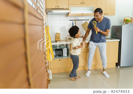 African American Father and his little boy dancing while cooking 92474033