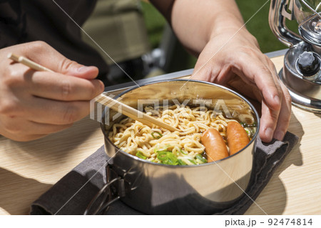 キャンプでインスタントラーメンを食べる男性 92474814