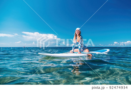 Woman sup sea. Happy healthy fit woman in bikini relaxing on a sup surfboard, floating on the clear turquoise sea water. Recreational Sports. Stand Up Paddle boarding. Summer fun, holidays travel. 92474934