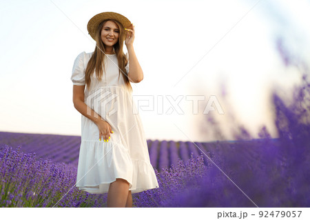 Young woman in a white dress walking in a lavender field 92479057