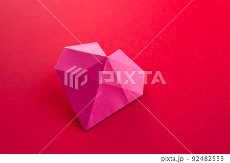 Pink paper heart origami isolated on a red background Pink paper heart origami isolated on a red background 92482553