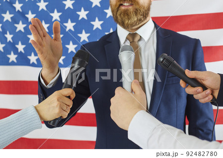 American politician speaking into several microphones of TV journalists at press conference 92482780