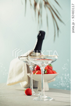 Bottle of champagne, two glasses and strawberries on sea and sky background. 92483117