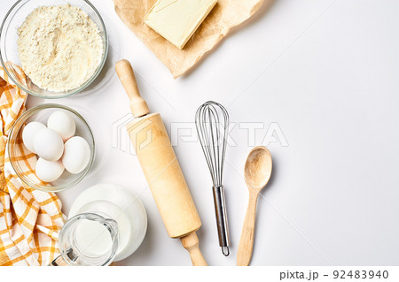 Preparation of the dough. A measurement of the amount of ingredients in the recipe. Ingredients for the dough: flour, eggs, rolling pin, whisk, milk, butter, cream. Top view, space for text 92483940