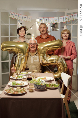Happy senior people standing by aged man with inflatable numbers 92485150