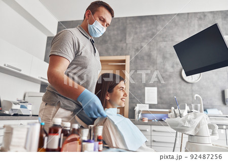 Confident male doctor is preparing young woman to dental survey 92487256