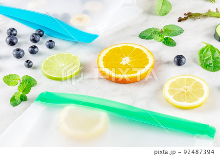 Food storage bags with fruit and vegetables, on a white marble kitchen table Food storage bags with fruit and vegetables, on a white marble kitchen table 92487394