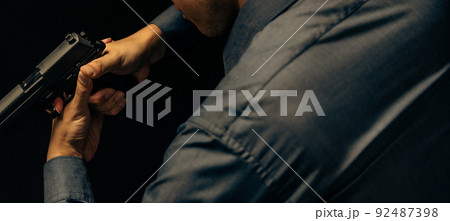 拳銃を構えるスーツの人物 92487398