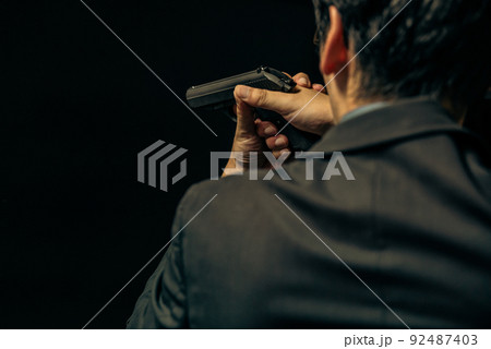 拳銃を構えるスーツの人物 92487403