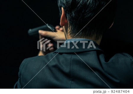 拳銃を構えるスーツの人物 92487404