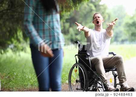 Woman walks away frustrated from man in wheelchair 92488463