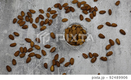 Roasted almonds are scattered on the table. Utensils with nuts on a white background Roasted almonds are scattered on the table. Utensils with nuts on a white background 92489906
